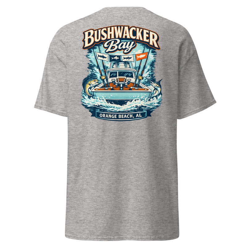 The back of a tee printed with a sportfishing tower boat running through whitewater, outriggers flying catch flags, billfish in the wake, and the Bushwacker Bay wordmark above Orange Beach, AL